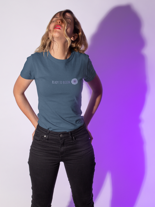 Young woman wearing deep teal color T-shirt with blooming flower illustration with "ready to bloom" quote